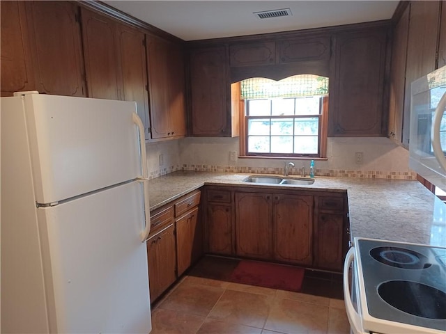 kitchen featuring white appliances, light countertops, visible vents, and a sink