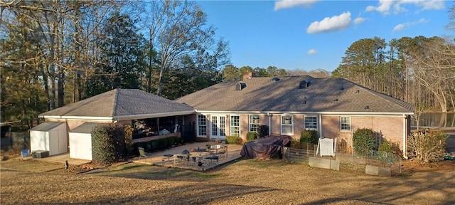 rear view of property with a patio, a shed, an outdoor structure, french doors, and brick siding