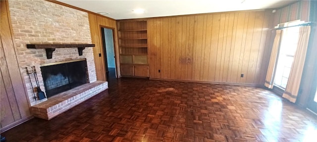 2104 Oak Bowery Rd, Opelika, AL 36801 - unfurnished living room with built in shelves, wood walls, baseboards, a brick fireplace, and ornamental molding