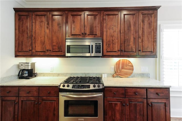 kitchen featuring appliances with stainless steel finishes and light stone counters