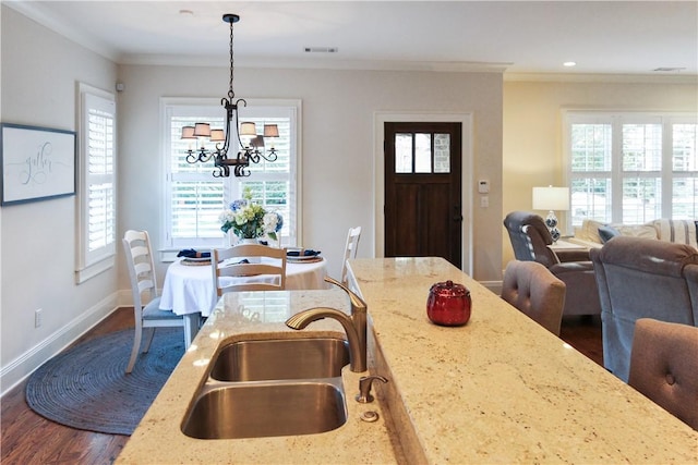 dining space with a notable chandelier, ornamental molding, sink, and dark wood-type flooring