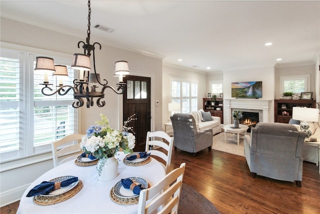 dining space with dark hardwood / wood-style floors, a healthy amount of sunlight, crown molding, and a chandelier