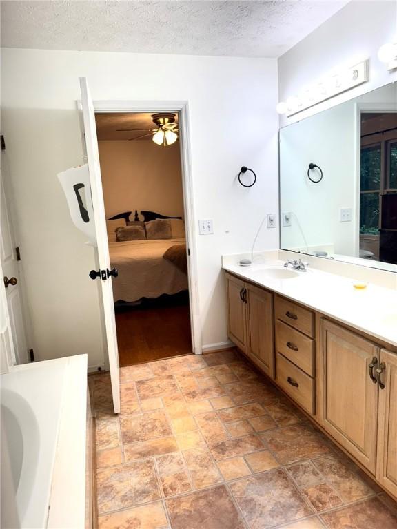 1377 E University Dr, Auburn, AL 36830 - full bathroom featuring ensuite bathroom, vanity, stone finish flooring, a textured ceiling, and ceiling fan