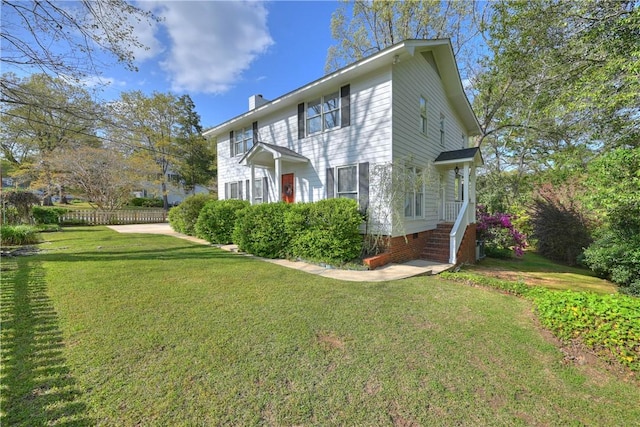 view of front of house featuring a chimney, a front yard, and fence