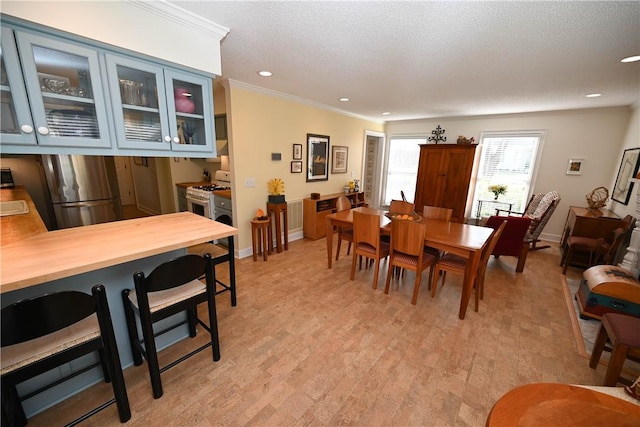dining space featuring a textured ceiling, light wood-style flooring, baseboards, ornamental molding, and recessed lighting