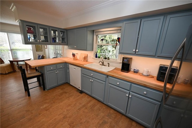 kitchen with a sink, wood counters, dishwasher, and a peninsula