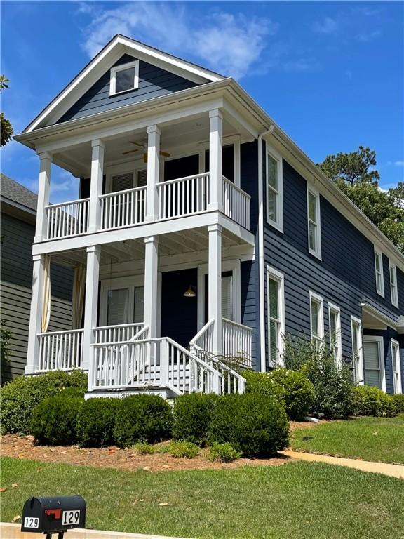 view of front of property featuring a balcony, a porch, and a front lawn