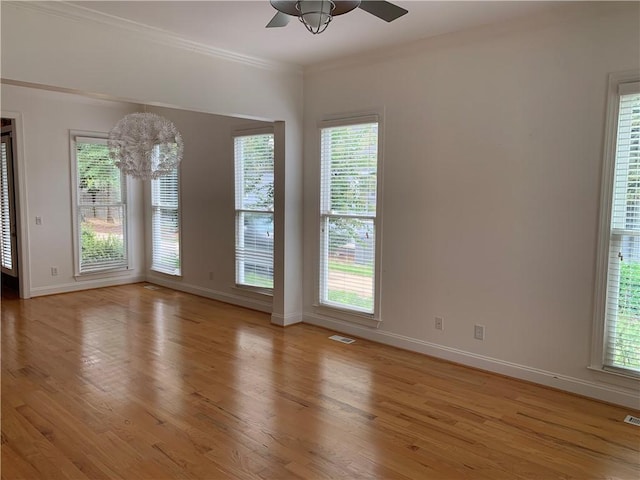 empty room with a ceiling fan, light wood finished floors, ornamental molding, and baseboards
