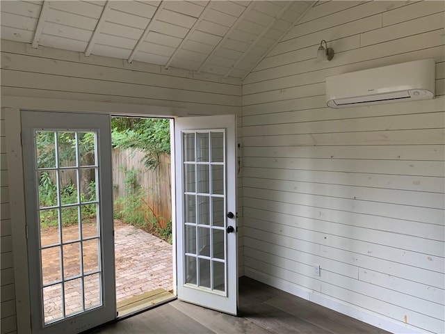 doorway featuring wooden walls, wood finished floors, an AC wall unit, and lofted ceiling