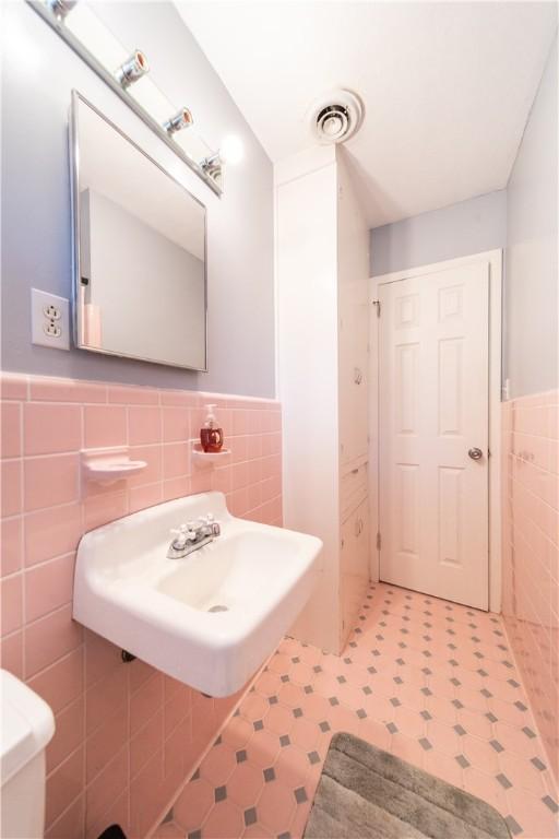 bathroom featuring sink and tile walls