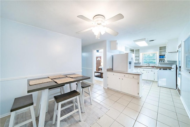 kitchen featuring white cabinetry, sink, ceiling fan, white appliances, and light tile patterned flooring