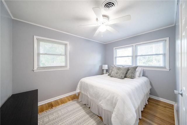 bedroom with light wood-type flooring, ceiling fan, and ornamental molding