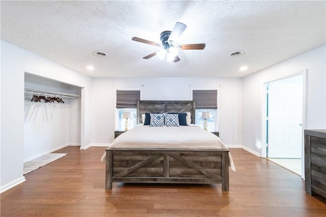 bedroom with a textured ceiling, a closet, ceiling fan, and dark hardwood / wood-style floors