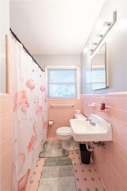 bathroom featuring toilet, plenty of natural light, tile walls, and sink