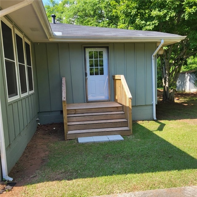 doorway to property with board and batten siding and a yard