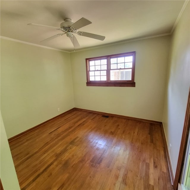 unfurnished room featuring crown molding, baseboards, and wood finished floors