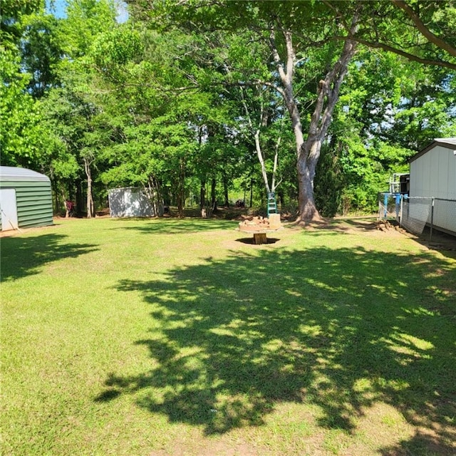 view of yard featuring a storage shed, fence, and an outbuilding