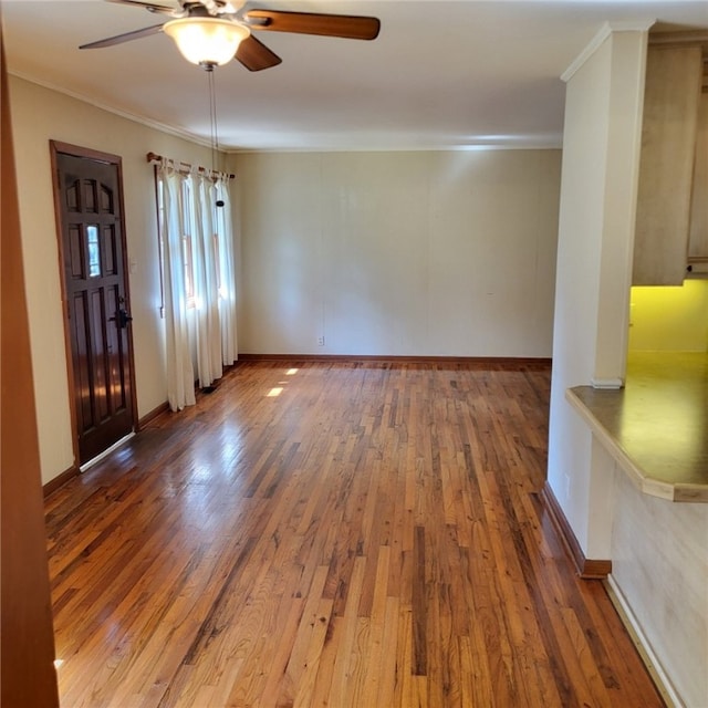 unfurnished room featuring crown molding, baseboards, ceiling fan, and wood finished floors