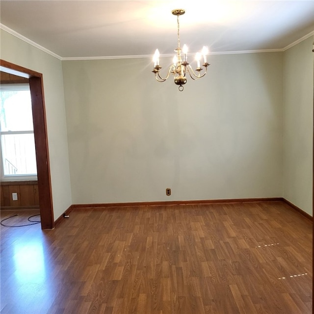 empty room featuring baseboards, ornamental molding, wood finished floors, and a notable chandelier