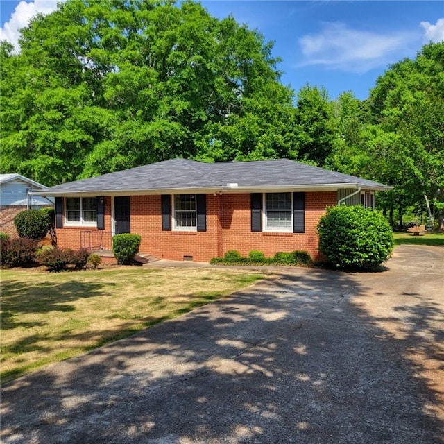 ranch-style house featuring concrete driveway, brick siding, a front yard, and roof with shingles