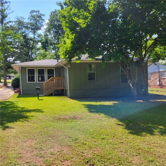 back of property with a lawn and board and batten siding