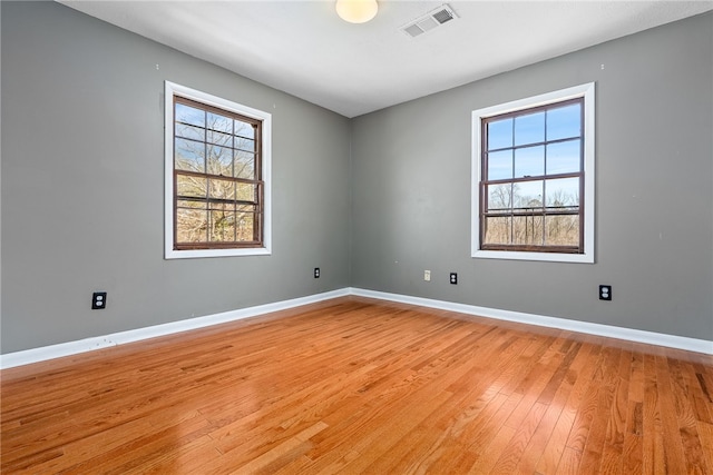 empty room featuring light wood-type flooring, baseboards, and visible vents