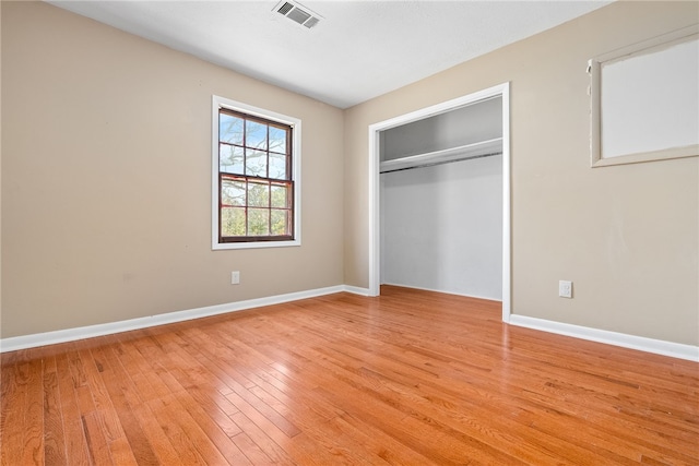 unfurnished bedroom featuring light wood finished floors, a closet, visible vents, and baseboards