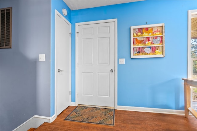 foyer entrance featuring wood finished floors, visible vents, and baseboards