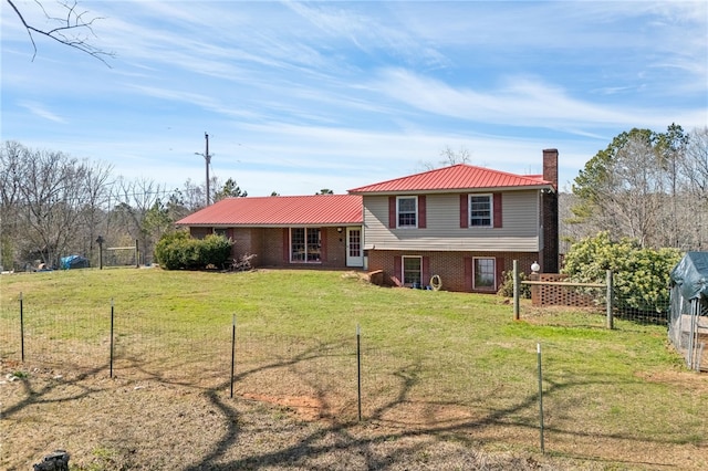 rear view of house with brick siding, a chimney, a lawn, metal roof, and fence