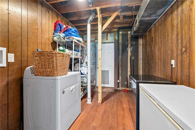 laundry room featuring laundry area, wood walls, light wood-type flooring, and washing machine and dryer