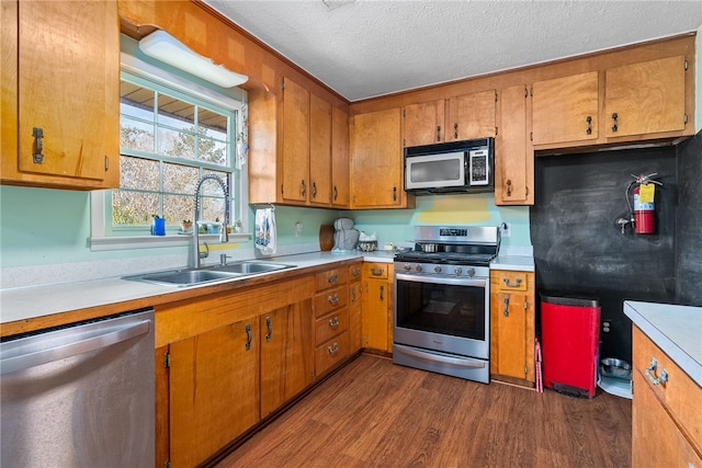 kitchen featuring appliances with stainless steel finishes, dark wood finished floors, light countertops, and a sink