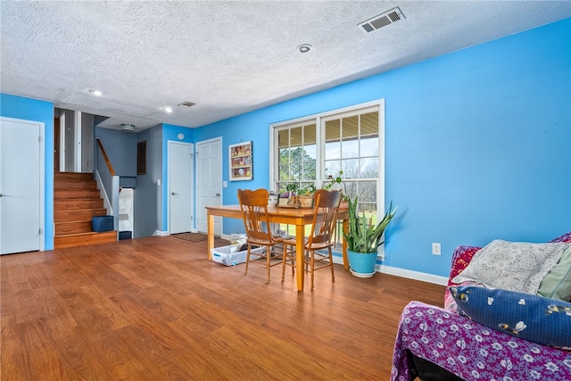 dining space with stairway, baseboards, visible vents, and wood finished floors