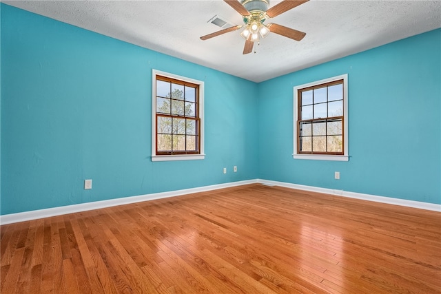 spare room with ceiling fan, wood finished floors, visible vents, and baseboards