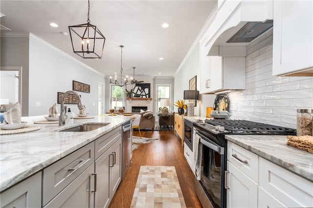 kitchen with white cabinetry, sink, light stone counters, pendant lighting, and appliances with stainless steel finishes