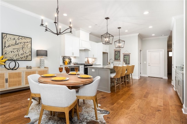 dining area with a notable chandelier, sink, wood-type flooring, and ornamental molding