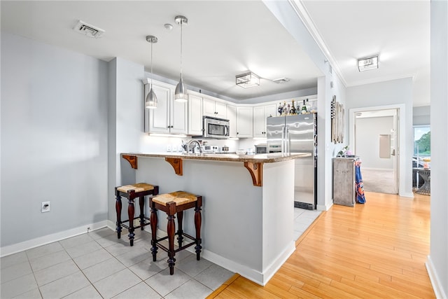 277 S Gay St Unit 601, Auburn, AL 36830 - kitchen featuring a breakfast bar area, appliances with stainless steel finishes, a peninsula, hanging light fixtures, and visible vents