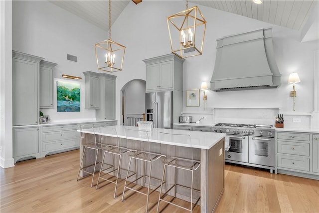 kitchen featuring a notable chandelier, gray cabinetry, custom range hood, high vaulted ceiling, and high quality appliances