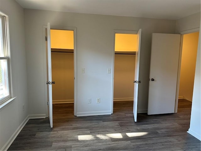 unfurnished bedroom featuring a spacious closet, a closet, and dark hardwood / wood-style floors