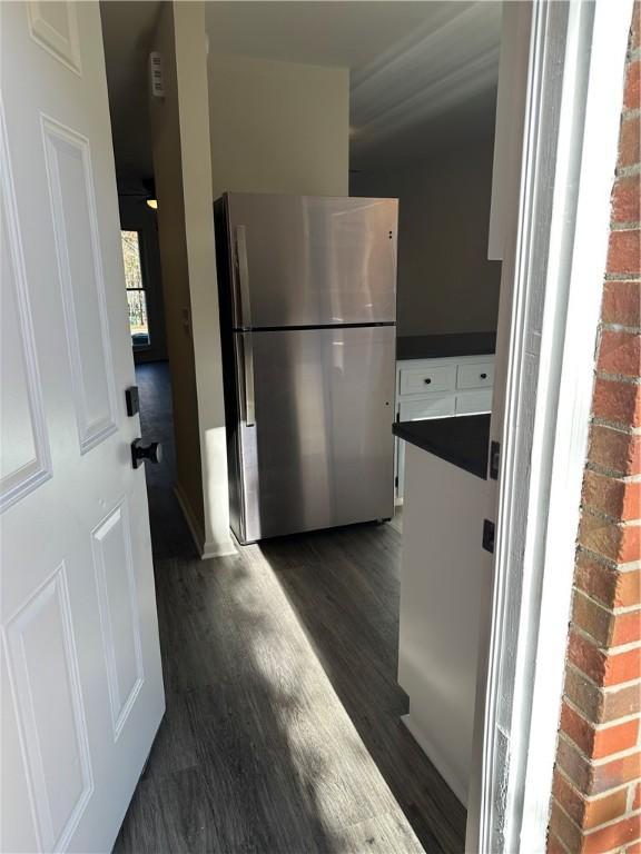 kitchen featuring stainless steel refrigerator, white cabinets, and dark wood-type flooring