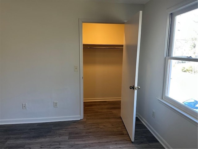 unfurnished bedroom featuring dark hardwood / wood-style flooring, a closet, and multiple windows