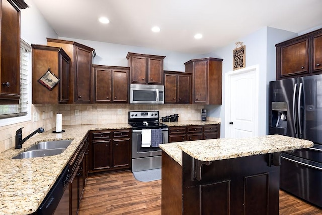 kitchen featuring sink, appliances with stainless steel finishes, dark hardwood / wood-style floors, a kitchen breakfast bar, and backsplash