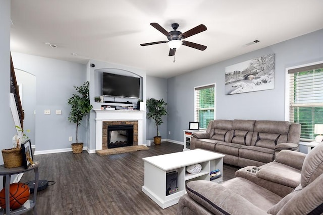 living room featuring ceiling fan, plenty of natural light, dark hardwood / wood-style floors, and a fireplace