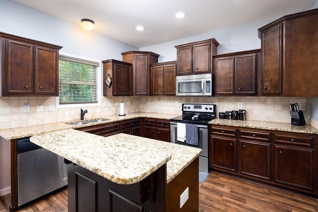 kitchen featuring sink, dark hardwood / wood-style flooring, light stone counters, stainless steel appliances, and dark brown cabinets