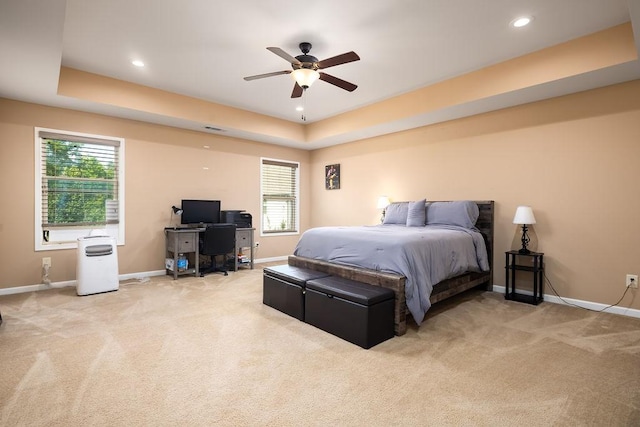 carpeted bedroom with ceiling fan and a raised ceiling