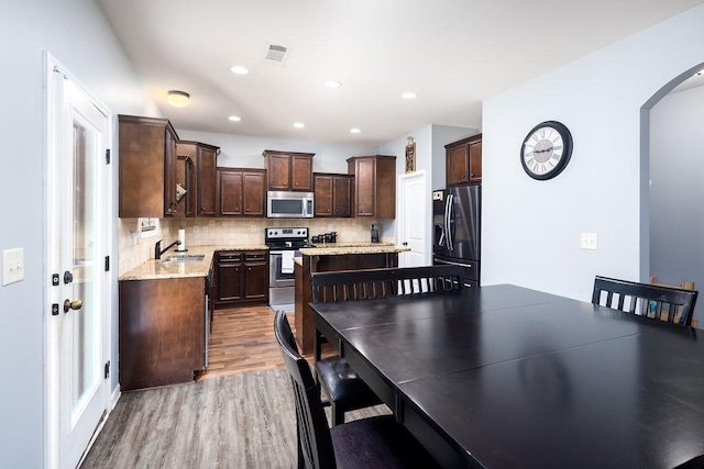 kitchen featuring light stone counters, appliances with stainless steel finishes, sink, and dark brown cabinets