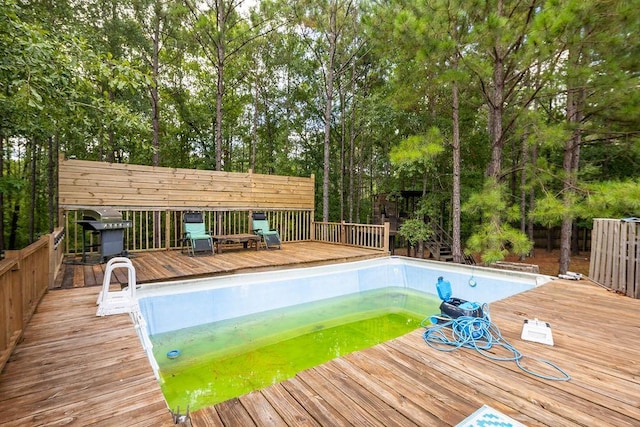 view of swimming pool with a wooden deck and grilling area