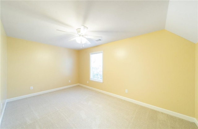 spare room featuring ceiling fan, light colored carpet, and vaulted ceiling