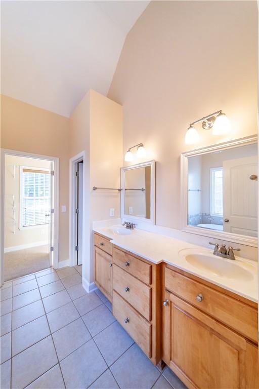 bathroom with tile patterned floors, a wealth of natural light, vanity, and lofted ceiling