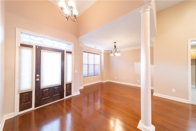 entryway featuring ornate columns, dark hardwood / wood-style flooring, ornamental molding, and a notable chandelier