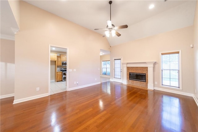 unfurnished living room featuring light wood-type flooring, ceiling fan, a healthy amount of sunlight, and a premium fireplace